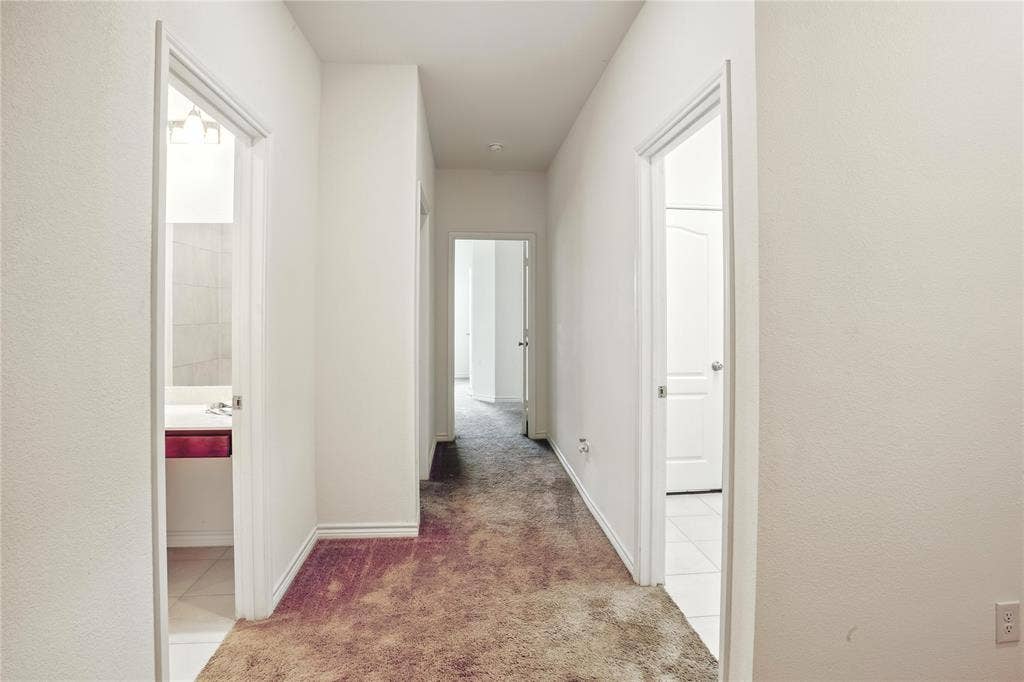 Hallway with carpet flooring and tile patterned floors