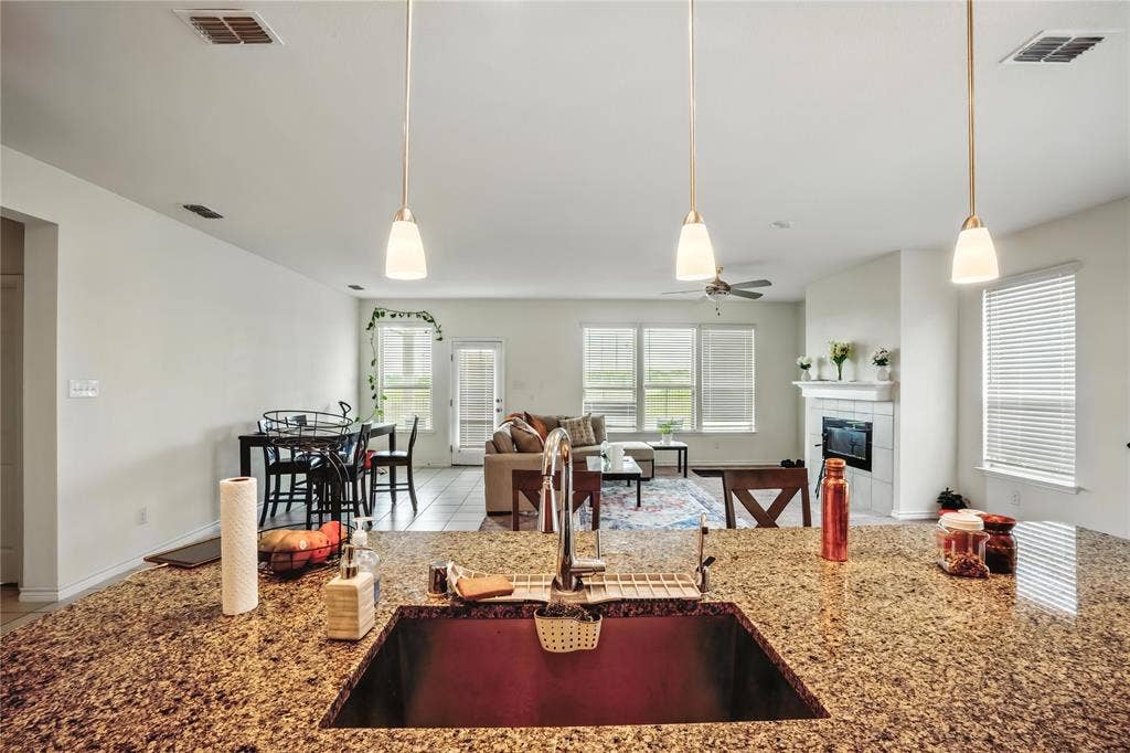 Kitchen with a fireplace, tile patterned flooring, stone countertops, and open floor plan