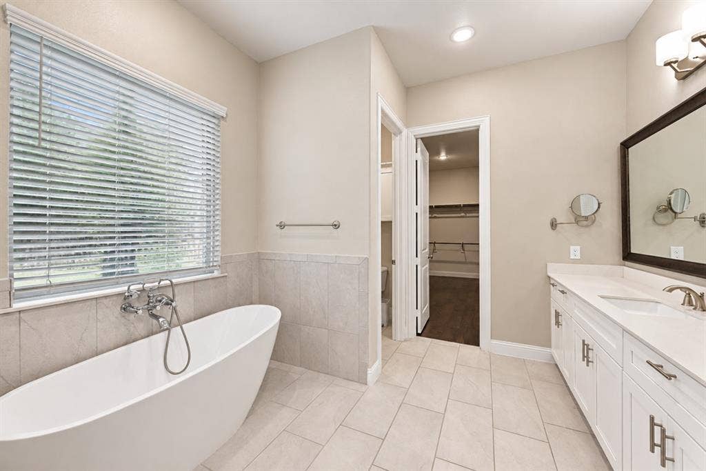 1603 Coventry Court, Farmers Branch, TX 75234 Freestanding soaking tub with wall-mounted faucet, dual vanity with undermount sinks, stone countertop, and tile flooring