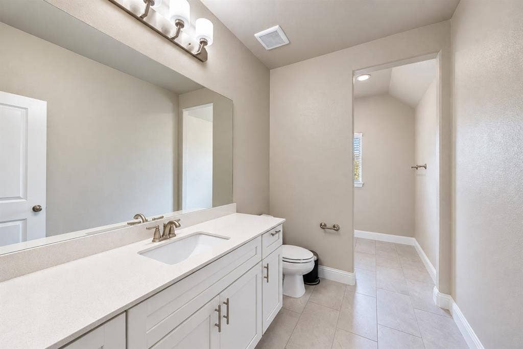 1603 Coventry Court, Farmers Branch, TX 75234 White vanity with brushed nickel hardware, expansive vanity mirror, light-toned countertop, and recessed lighting