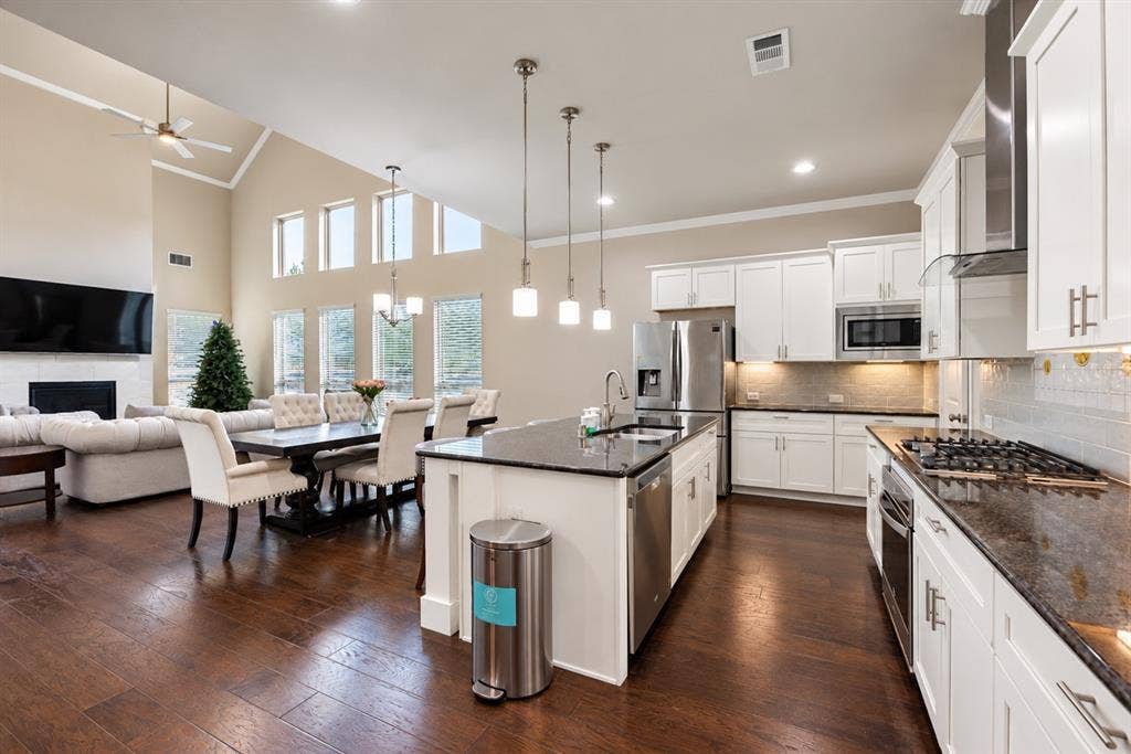 1603 Coventry Court, Farmers Branch, TX 75234 Spacious interior featuring soaring ceilings, wood-finish flooring, a contemporary fireplace, a kitchen island with pendant lighting, and stainless steel appliances