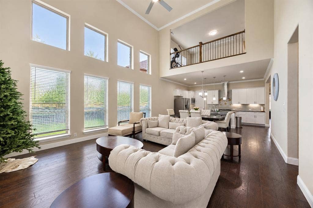 1603 Coventry Court, Farmers Branch, TX 75234 Two-story living area featuring dark wood-finish flooring, high ceilings, and multiple windows with blinds