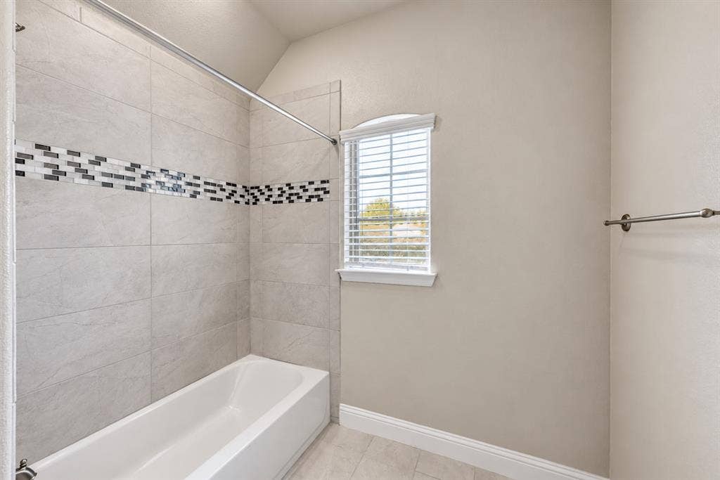 1603 Coventry Court, Farmers Branch, TX 75234 Bathtub with floor-to-ceiling tile surround, mosaic tile accent, and a window with blinds