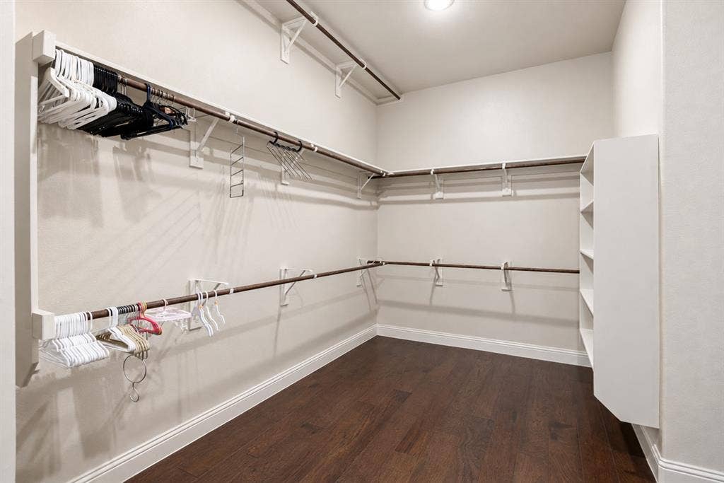 1603 Coventry Court, Farmers Branch, TX 75234 Walk-in closet with dark wood-finish flooring, white built-in shelving, and multiple clothing rods