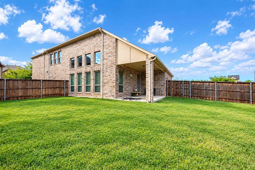 1603 Coventry Court, Farmers Branch, TX 75234 Expansive green lawn, wood fence, brick exterior, covered patio, and multiple windows