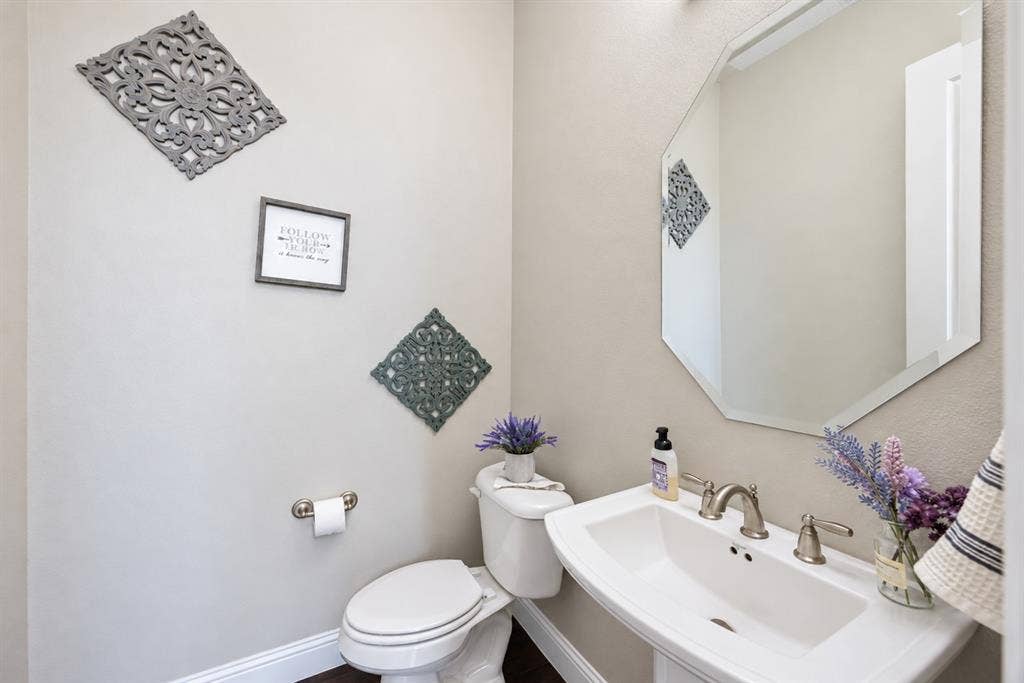 1603 Coventry Court, Farmers Branch, TX 75234 Pedestal sink with brushed nickel faucet, octagonal wall mirror, and neutral wall paint