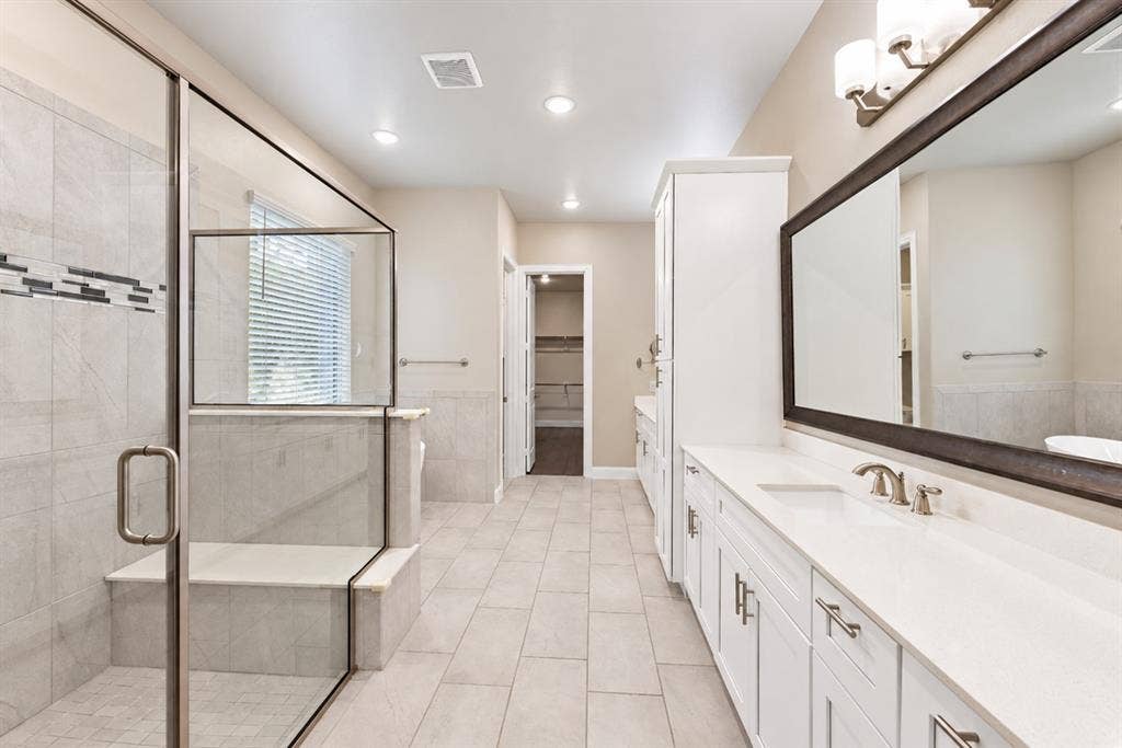 1603 Coventry Court, Farmers Branch, TX 75234 Glass-enclosed shower with integrated bench seating, dual vanity with undermount sinks, and a full-width mirror with decorative lighting