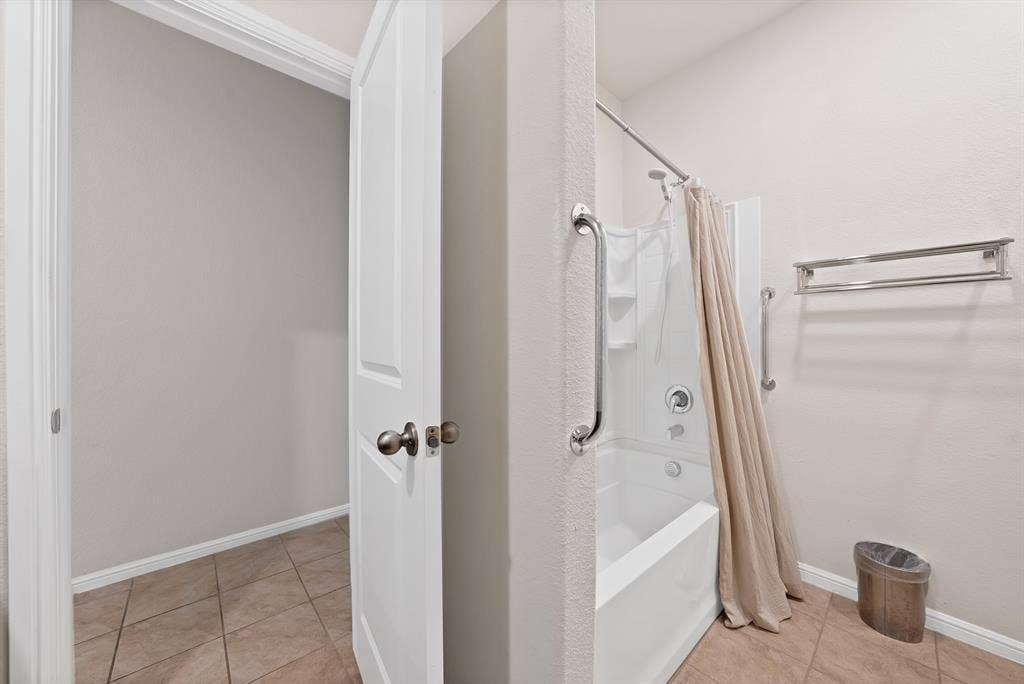 228 Foxhunter Street, Fort Worth, TX 76131 Bathtub with built-in shower, stainless steel grab bars, and tile flooring