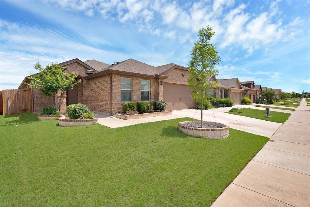 228 Foxhunter Street, Fort Worth, TX 76131 Brick exterior residence featuring an attached garage, a well-maintained lawn, and a sidewalk