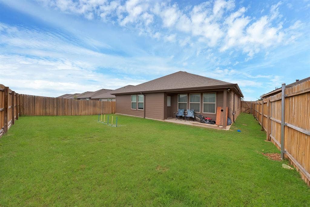 228 Foxhunter Street, Fort Worth, TX 76131 Expansive grassy backyard featuring a full privacy fence, concrete patio, and exterior siding