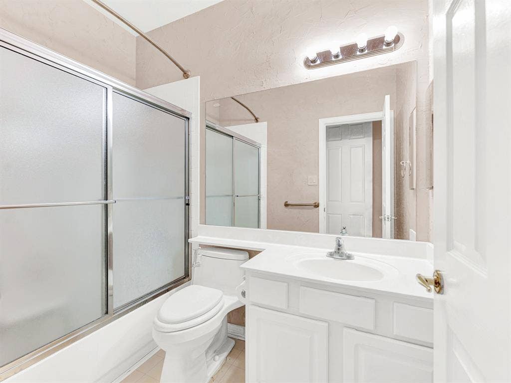 Frosted sliding doors enclose the tub and shower, preserving privacy while the broad vanity mirror reflects light throughout the bathroom. Rinse off after a day of exploring and get ready for a relaxed supper at home.