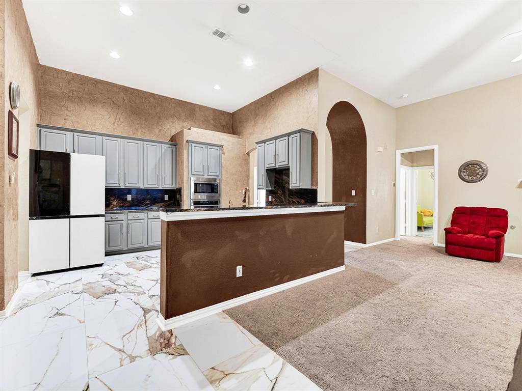 A wraparound kitchen layout keeps appliances and work surfaces within easy reach, while open walkways at either end connect it to surrounding rooms. Move comfortably through Sunday meal prep, then join everyone nearby for a well-earned break.