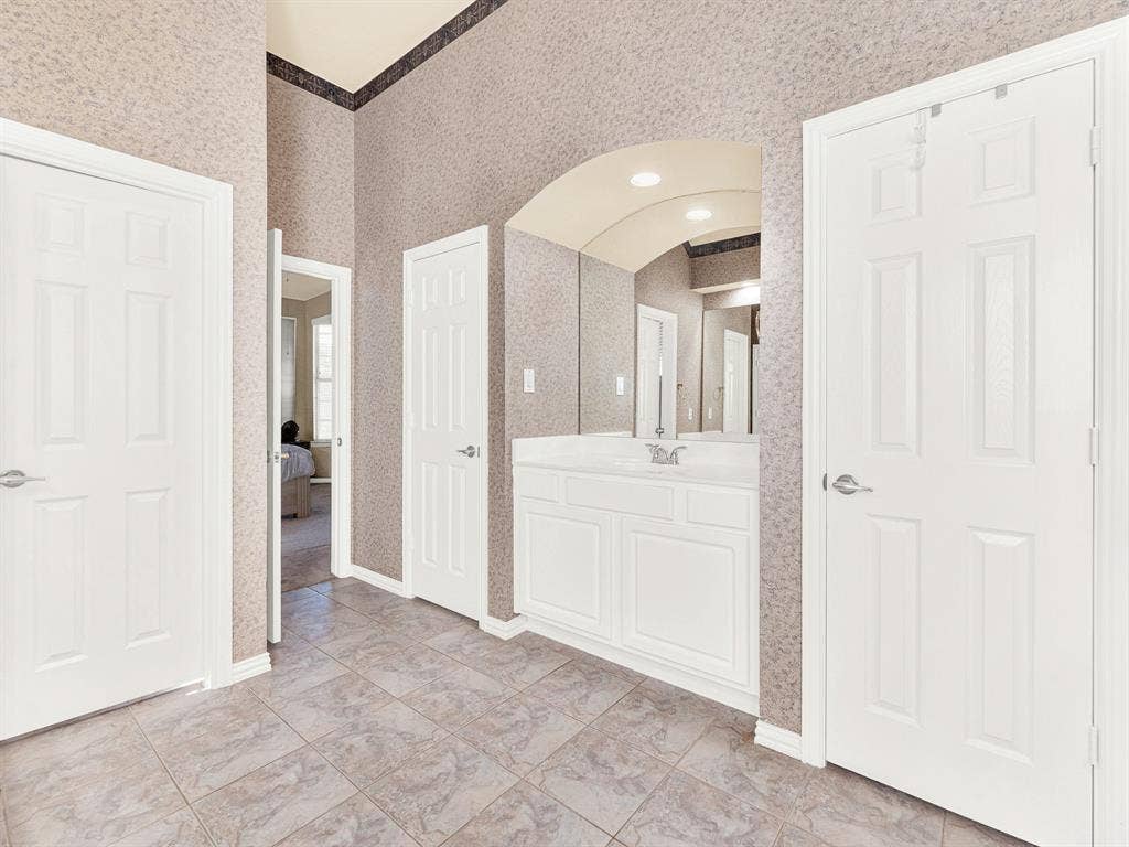 A second vanity occupies its own arched recess, offering a separate preparation space beneath bright overhead lighting. Get ready together in the morning with room for each person’s routine.