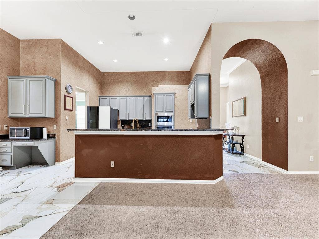 Recessed ceiling lights brighten the kitchen evenly, while warm textured walls give the space depth beyond the cabinetry. Spend an evening teaching someone a cherished family recipe, one delicious step at a time.