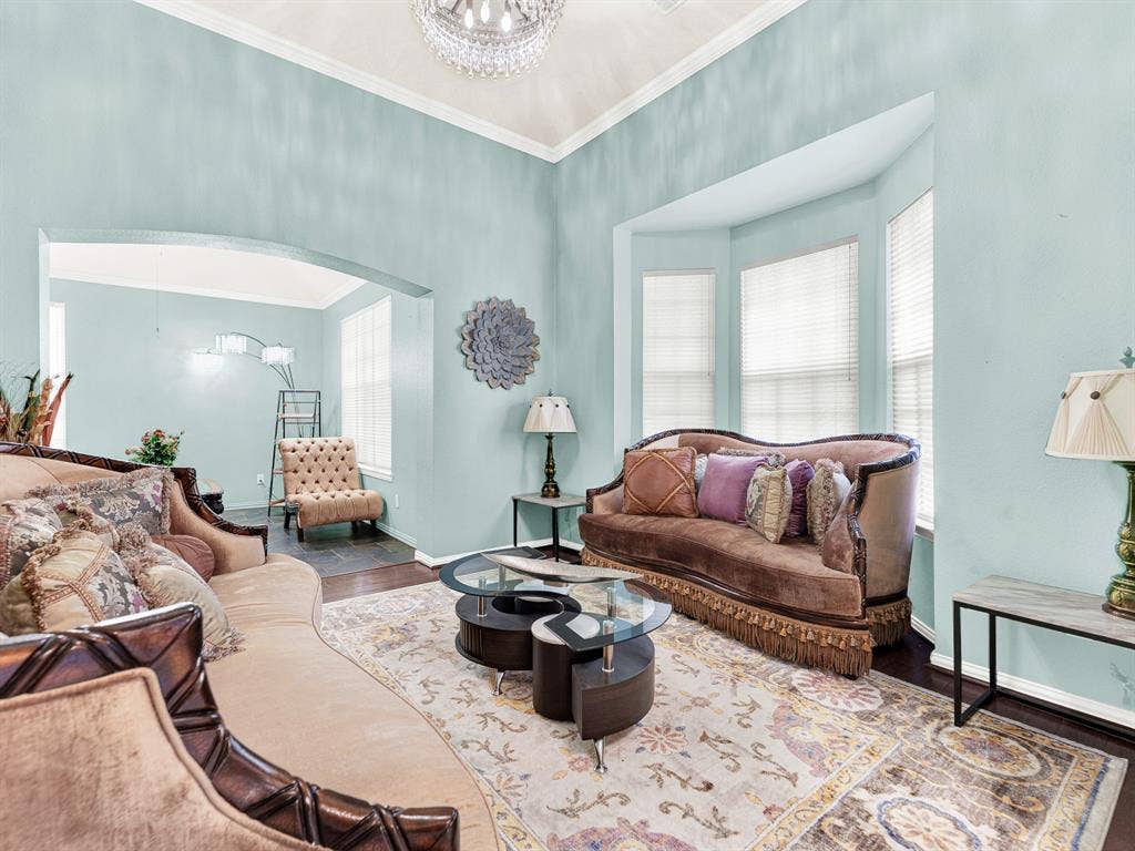 A crystal ceiling fixture scatters light across the living room, adding sparkle above warm wood-toned flooring. Enjoy an after-dinner conversation in a separate gathering space away from the television.