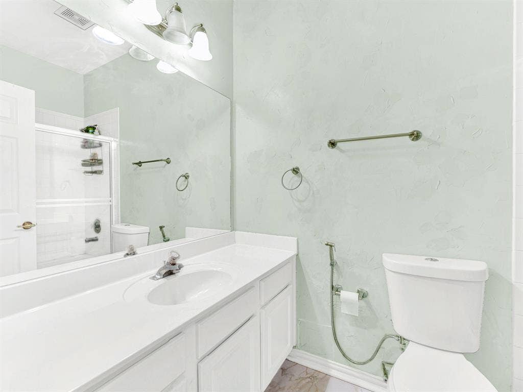 Pale green walls and a wide mirror soften and brighten the bathroom, with a long white vanity providing useful counter space. Freshen up before guests arrive and enjoy an easy start to the evening.