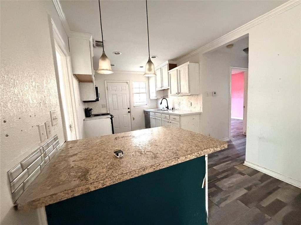 Kitchen featuring white cabinetry, stone-finish countertops, subway tile backsplash, and pendant lighting