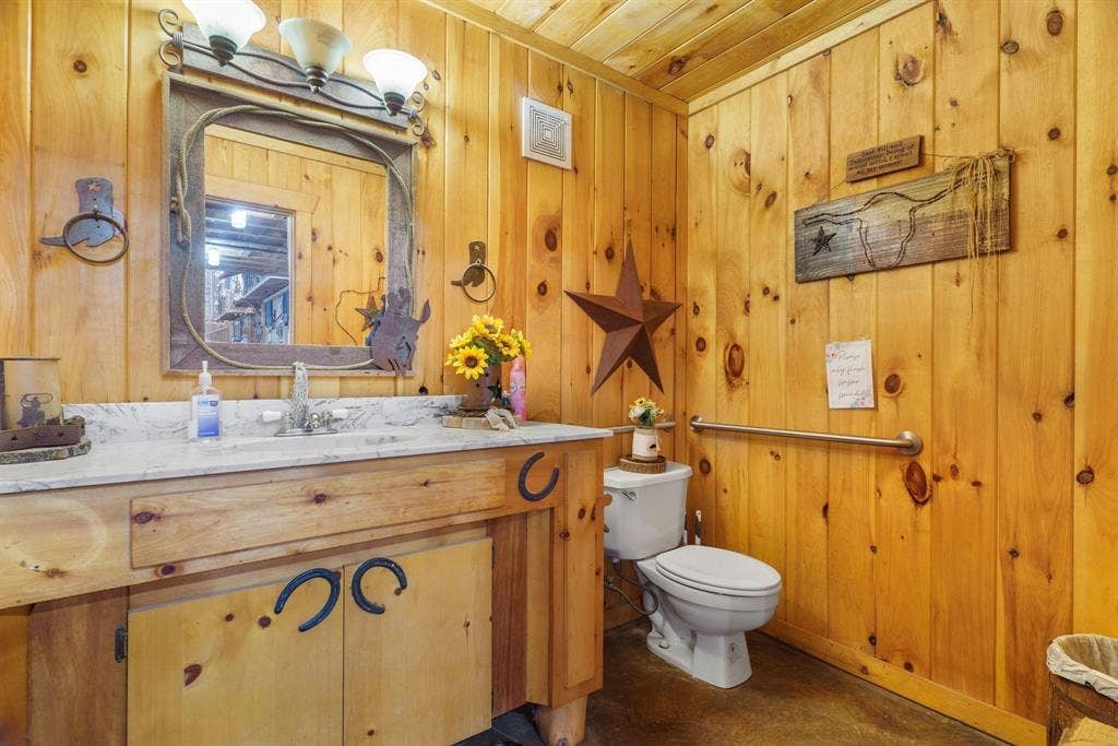 8685 FM 1827, Anna, TX 75409 Bathroom featuring knotty pine wall paneling, a custom wood vanity with a stone countertop, an integrated sink, and an attached three-light fixture
