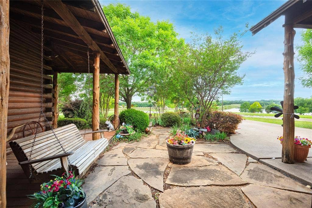 8685 FM 1827, Anna, TX 75409 Log exterior with covered porch featuring natural log support posts and irregular flagstone paving