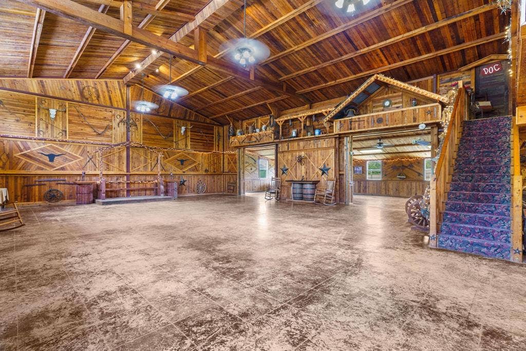 8685 FM 1827, Anna, TX 75409 Expansive open-concept interior featuring vaulted wood-paneled ceilings with exposed rafters, full-height wood wall paneling, polished concrete flooring, and a built-in elevated loft structure