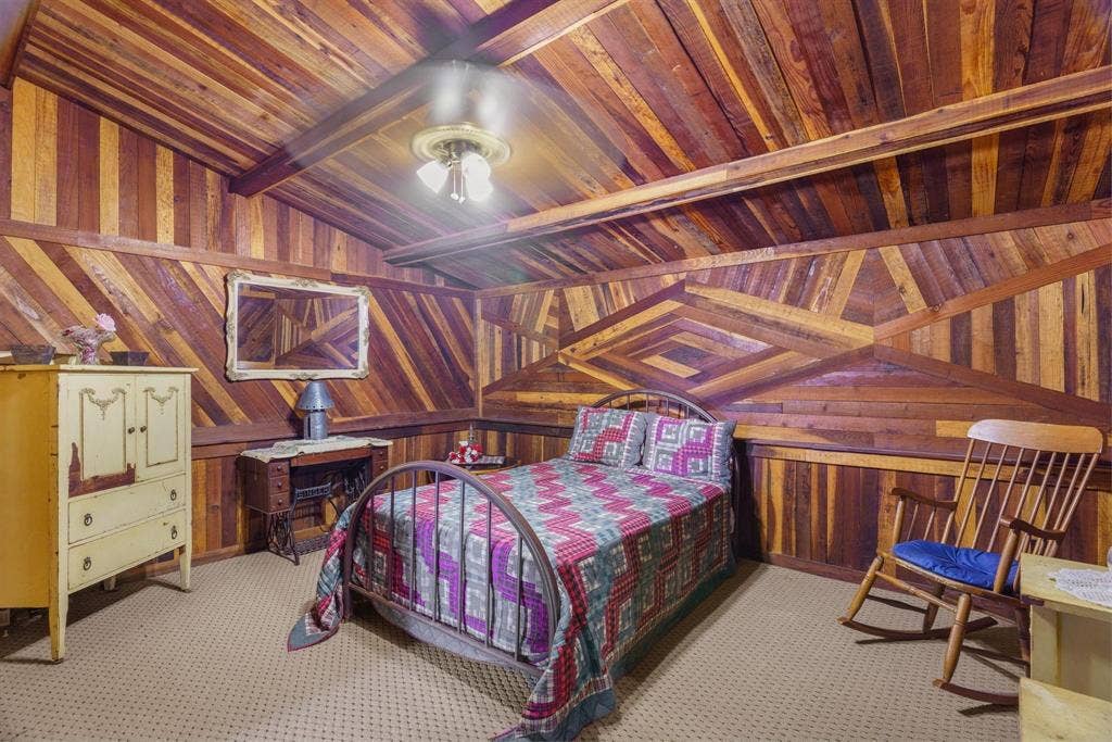 8685 FM 1827, Anna, TX 75409 Geometric wood-paneled walls and vaulted ceilings featuring exposed wood-plank finish, wall-mounted mirror, and central multi-bulb ceiling fixture