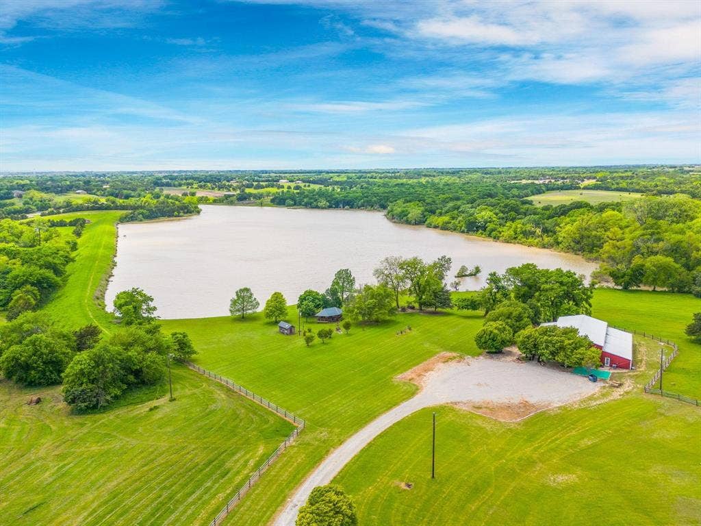 8685 FM 1827, Anna, TX 75409 Expansive acreage featuring private waterfront access, open pasture land, mature trees, and a multi-purpose barn structure