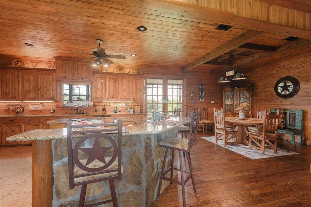 8685 FM 1827, Anna, TX 75409 Kitchen featuring wood-paneled walls and ceilings, stone-faced kitchen island with a stone countertop, wood-finish cabinetry, and wood-finish flooring