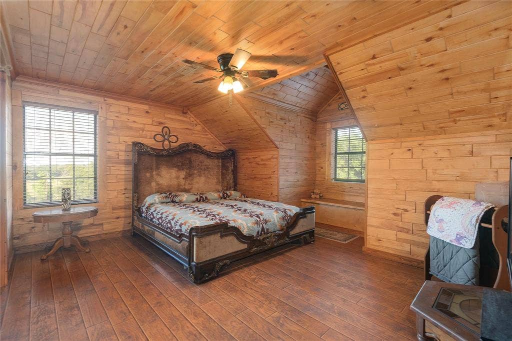 8685 FM 1827, Anna, TX 75409 Wood-planked walls and vaulted ceilings featuring exposed wood-finish paneling, wood-finish flooring, and a central ceiling fan with integrated light fixture