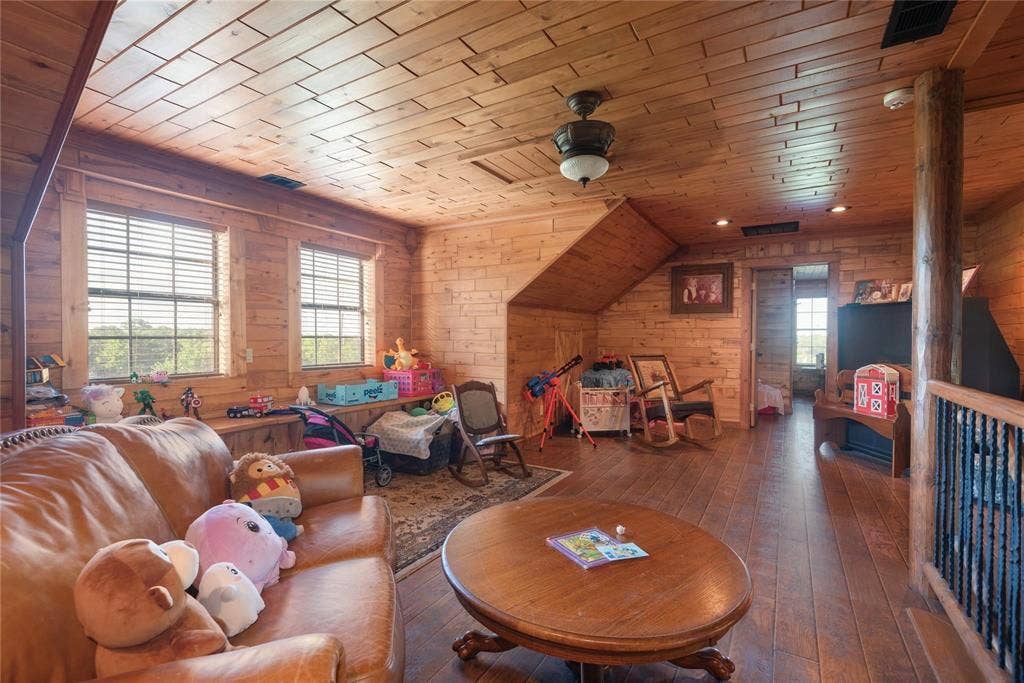 8685 FM 1827, Anna, TX 75409 Interior space featuring natural wood wall paneling, plank wood-finish flooring, a vaulted plank-paneled ceiling, and a prominent wood support column