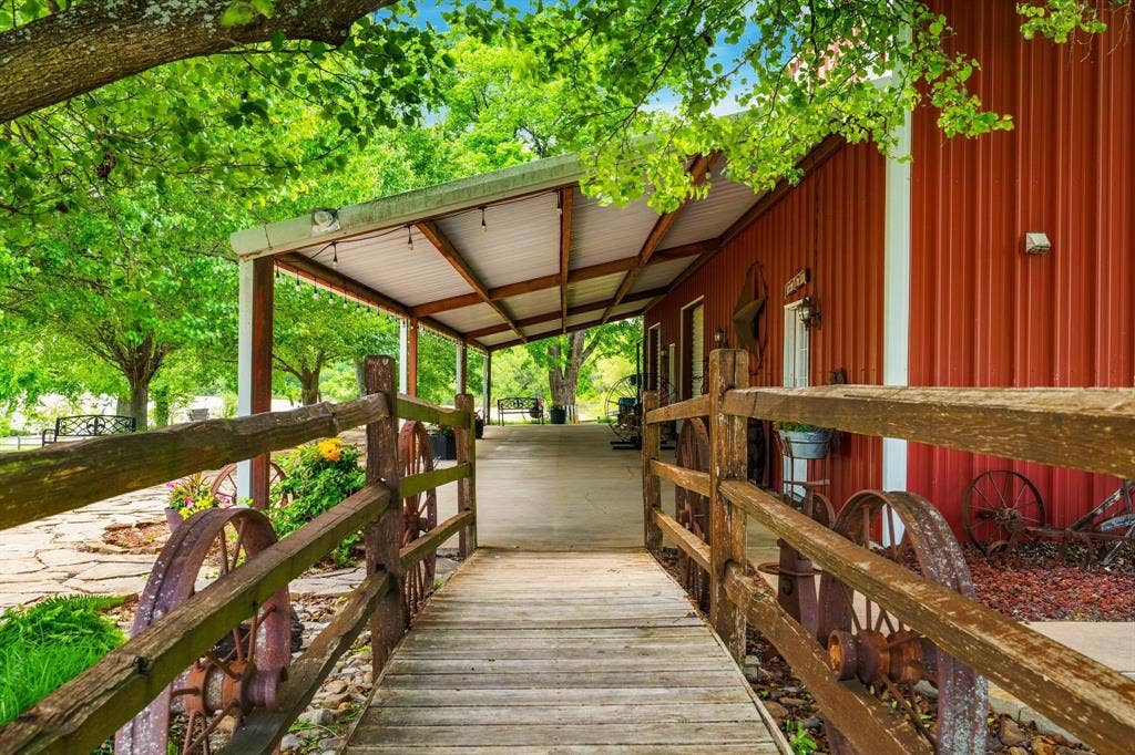8685 FM 1827, Anna, TX 75409 Covered porch with exposed wood rafters, metal siding exterior, wood-plank walkway, and rustic timber-rail fencing
