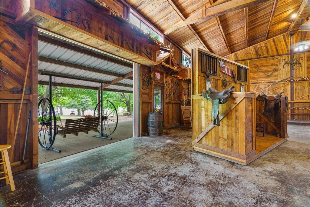 8685 FM 1827, Anna, TX 75409 Interior space featuring extensive wood-paneled walls and exposed timber ceiling beams, concrete flooring, and a large opening to a covered outdoor area