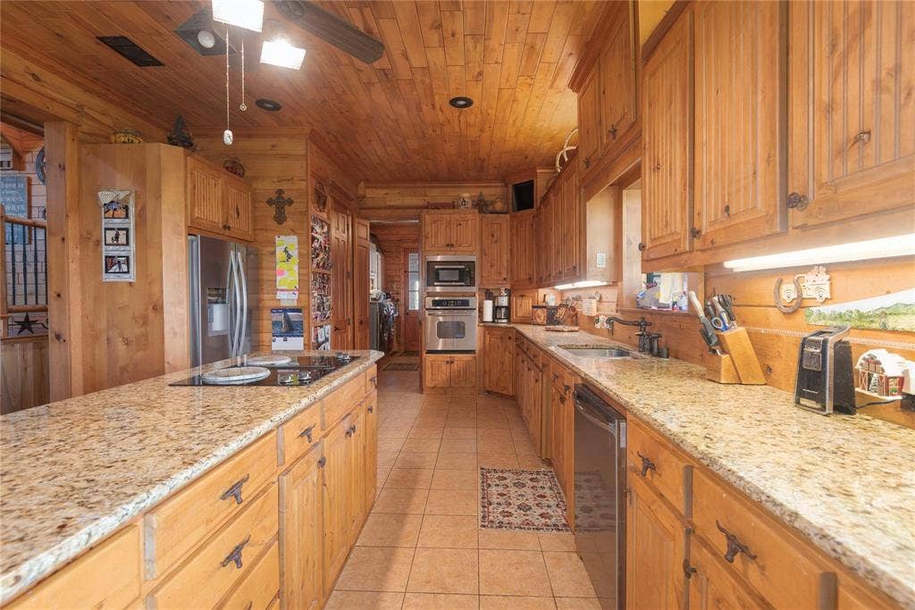 8685 FM 1827, Anna, TX 75409 Kitchen featuring solid wood cabinetry, stone-surface countertops, built-in double wall ovens, a center island with an integrated cooktop, and wood-paneled ceiling