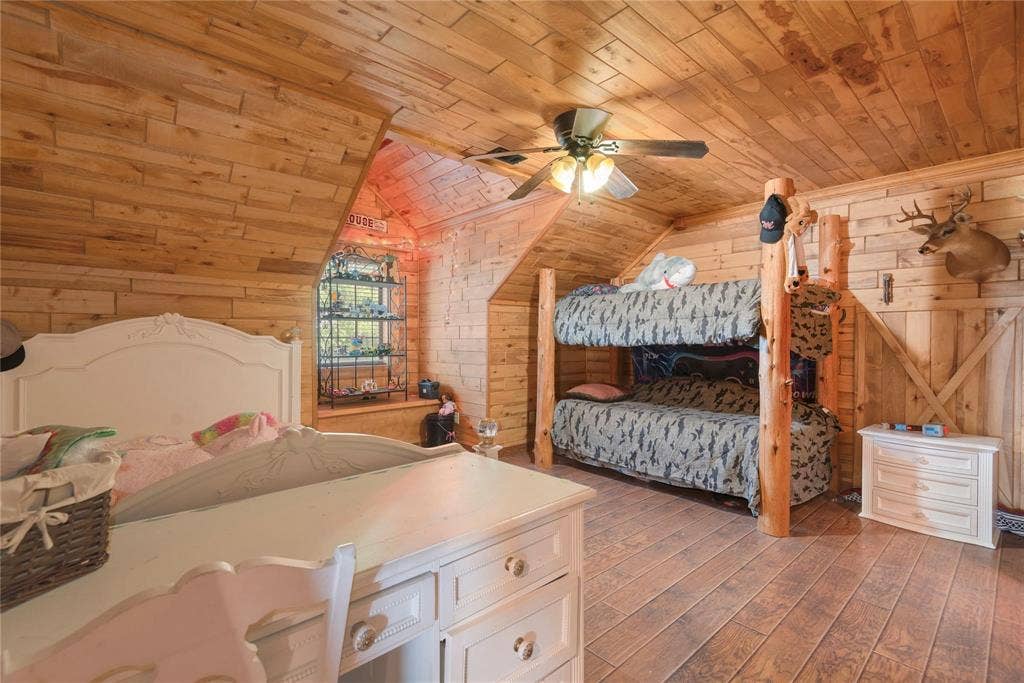 8685 FM 1827, Anna, TX 75409 Room featuring natural wood plank walls and ceiling, exposed timber support posts, a built-in recessed shelving nook, and a ceiling fan with integrated lighting