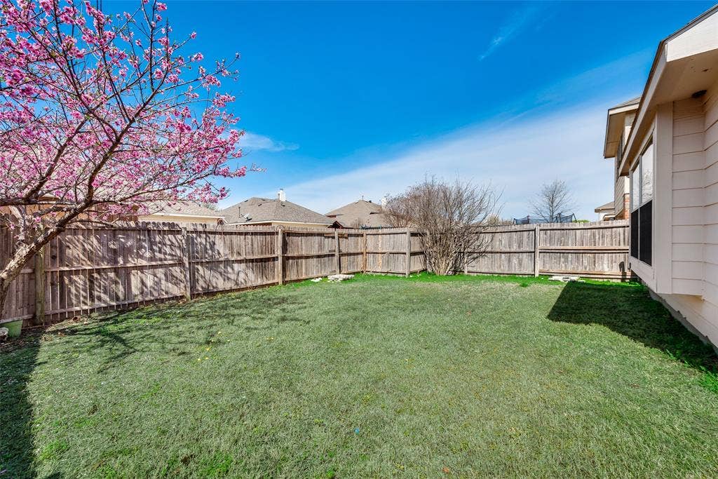 1545 Crystal Pass, Allen, TX 75002 Expansive backyard featuring a manicured lawn, full privacy fencing, and a mature flowering tree