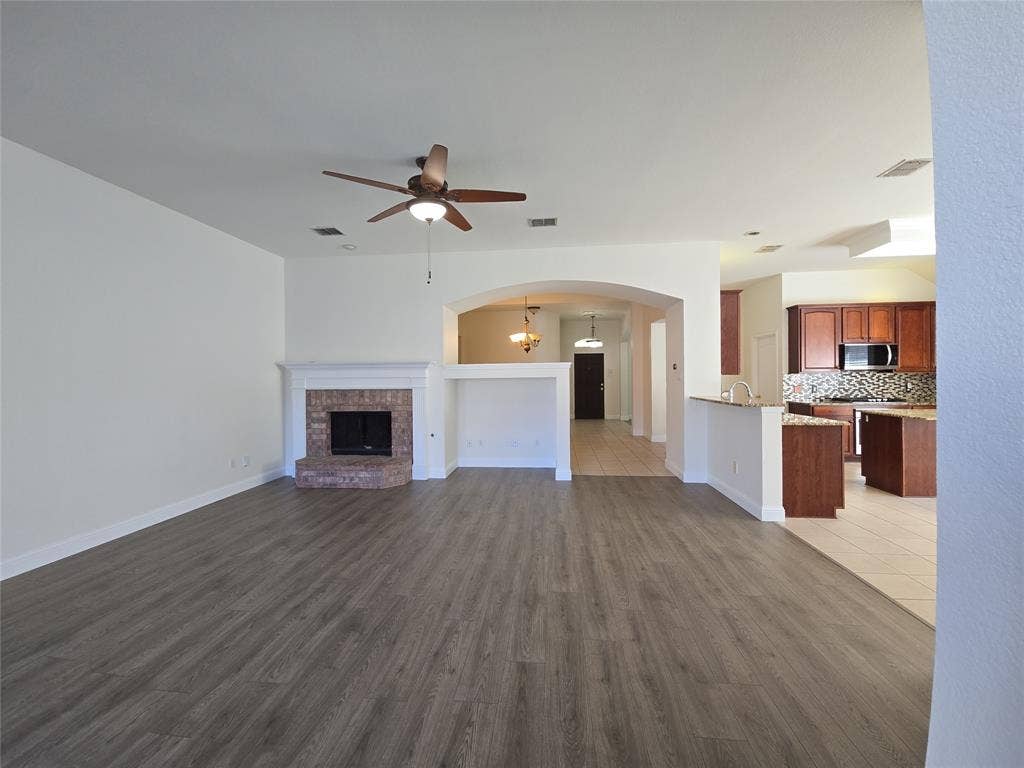 1545 Crystal Pass, Allen, TX 75002 Spacious living area featuring wood-finish flooring, a brick fireplace with a white mantel, and an overhead ceiling fan