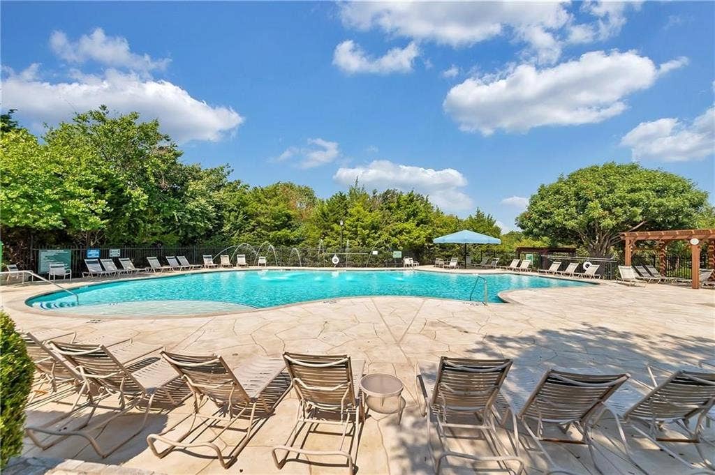 1545 Crystal Pass, Allen, TX 75002 Expansive resort-style swimming pool featuring water fountains, a surrounding stone paver deck, and a shaded pergola area