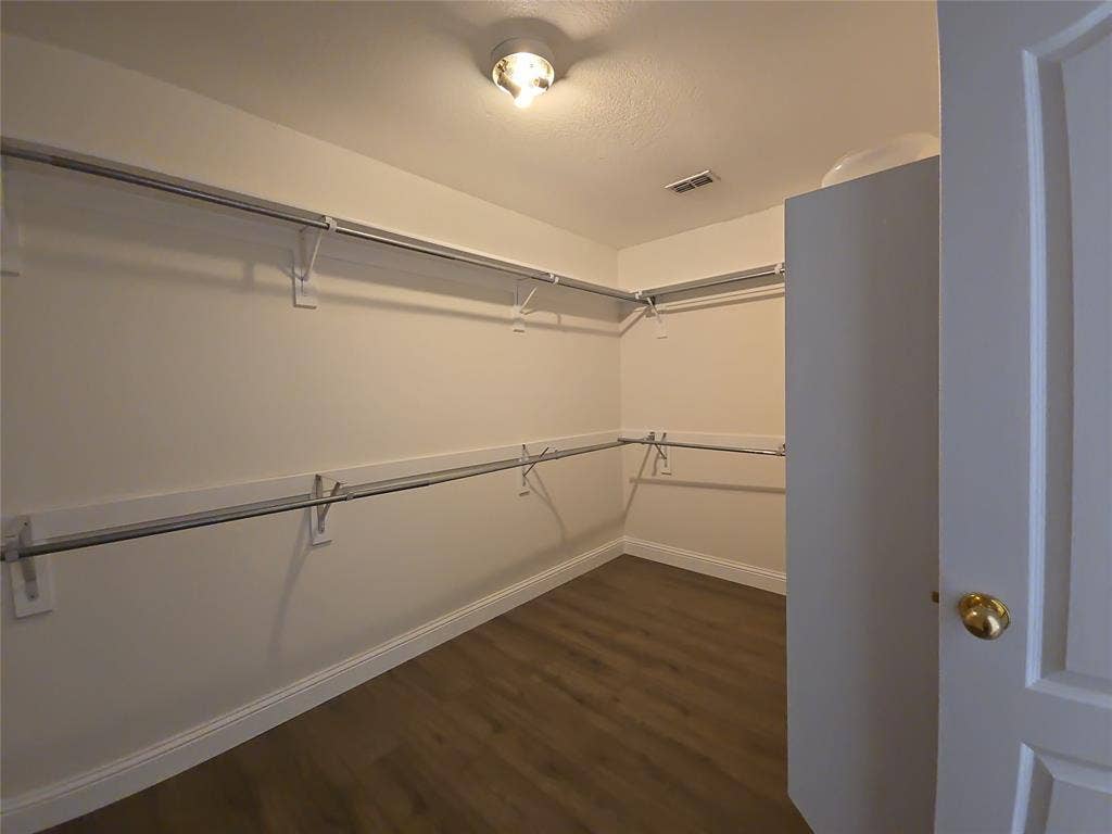 1545 Crystal Pass, Allen, TX 75002 Spacious walk-in closet with wood-finish flooring, extensive built-in shelving, and hanging rods