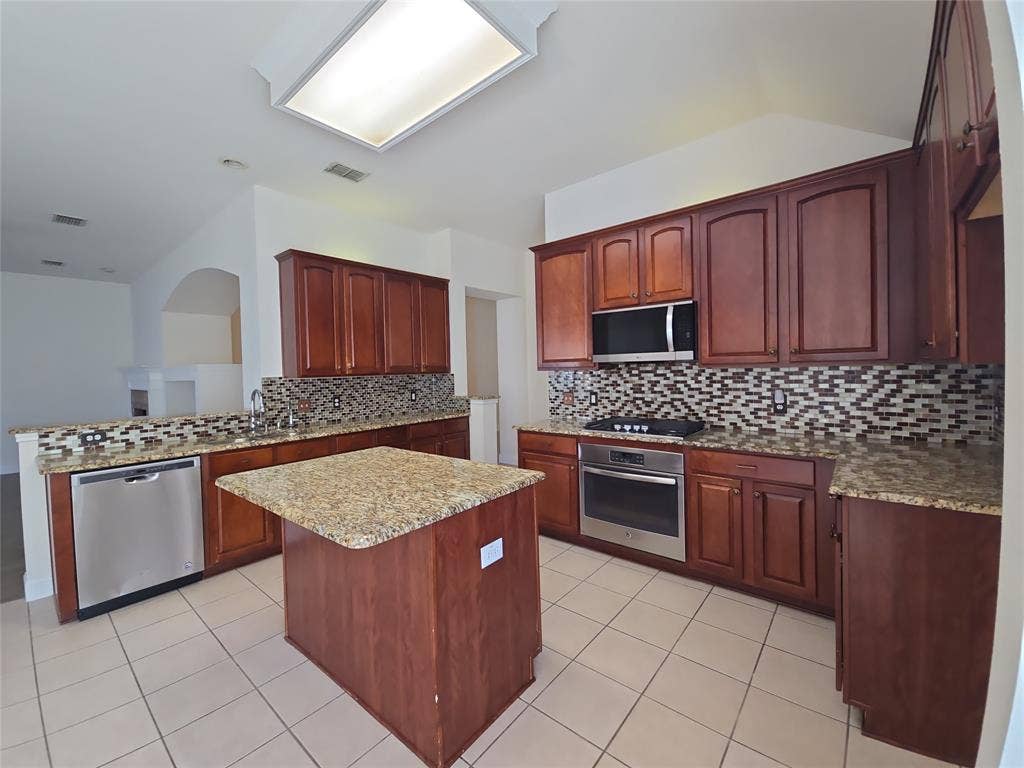 1545 Crystal Pass, Allen, TX 75002 Kitchen featuring rich wood cabinetry, stainless steel appliances, granite countertops, and a mosaic tile backsplash