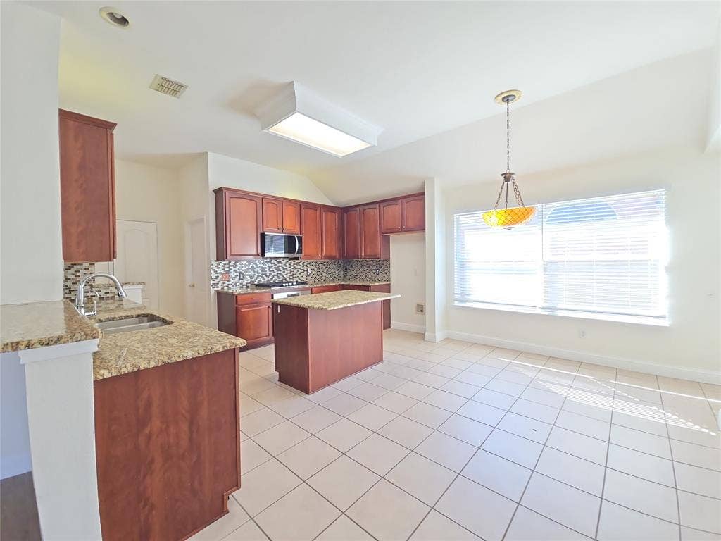 1545 Crystal Pass, Allen, TX 75002 Kitchen featuring wood cabinetry, a center island, granite countertops, and a tile backsplash