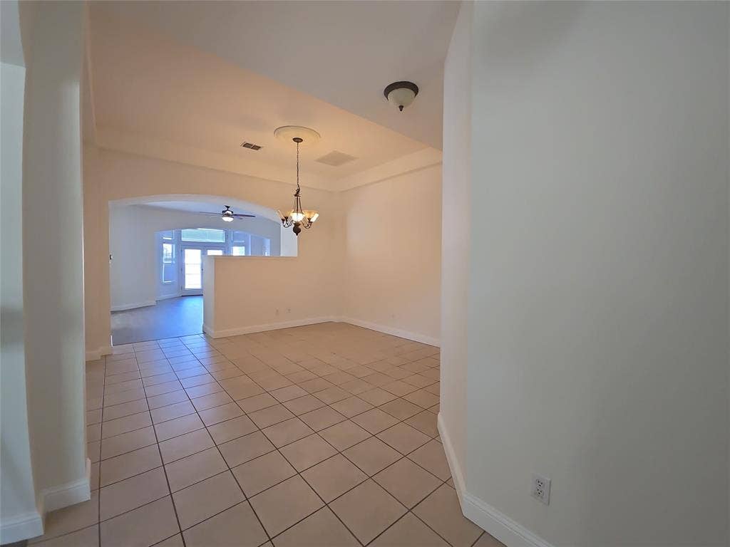 1545 Crystal Pass, Allen, TX 75002 Tiled flooring, arched entryway, tray ceiling with decorative medallion, and a chandelier lighting fixture