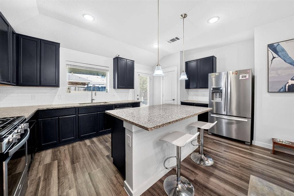 5534 Yarborough Drive, Forney, TX 75126 Kitchen featuring dark cabinetry, light countertops, wood-finish flooring, stainless steel appliances, and an island with pendant lighting