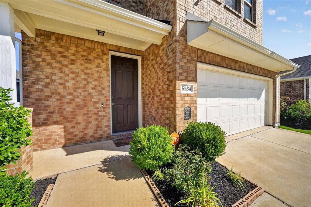 5534 Yarborough Drive, Forney, TX 75126 Welcoming brick front elevation with a covered entry featuring a dark wood door and sidelights