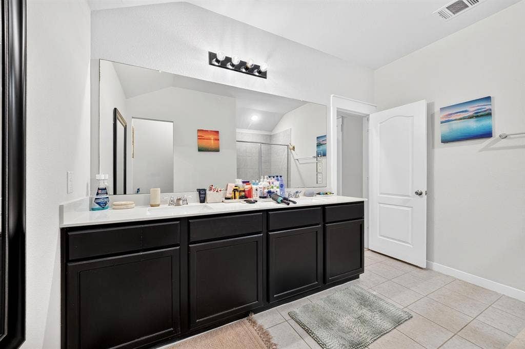 5534 Yarborough Drive, Forney, TX 75126 Dual vanity with white countertop, dark wood-finish cabinetry, and a large wall-mounted mirror