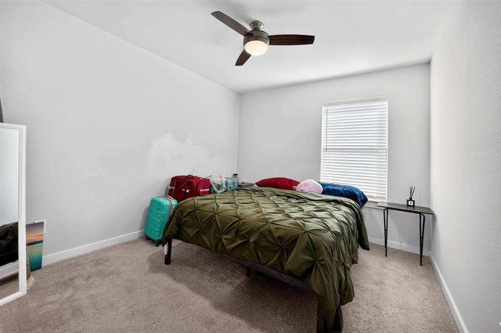 5534 Yarborough Drive, Forney, TX 75126 Spacious primary bedroom showcasing rich wood-finish furnishings, neutral carpeting, and abundant natural light from large windows dressed in golden drapery