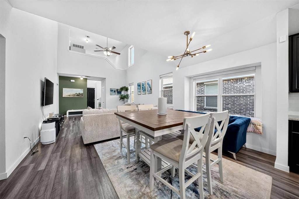 5534 Yarborough Drive, Forney, TX 75126 Open-concept dining and kitchen area featuring wood-finish flooring throughout, a dining table with seating for multiple guests, modern pendant lighting, and abundant natural light from large windows
