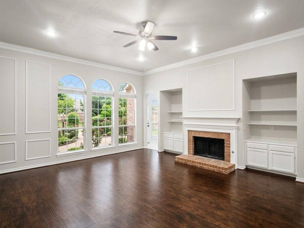 2609 Townshed Drive, Garland, TX 75044 Hardwood flooring, three arched windows, a brick fireplace, built-in shelving, and a ceiling fan