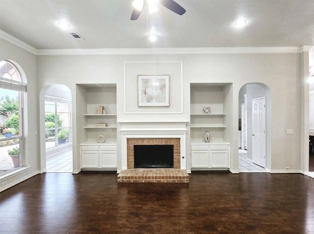 2609 Townshed Drive, Garland, TX 75044 Brick fireplace with white mantel and hearth, built-in shelving and cabinetry, wood-finish flooring, and recessed ceiling lighting