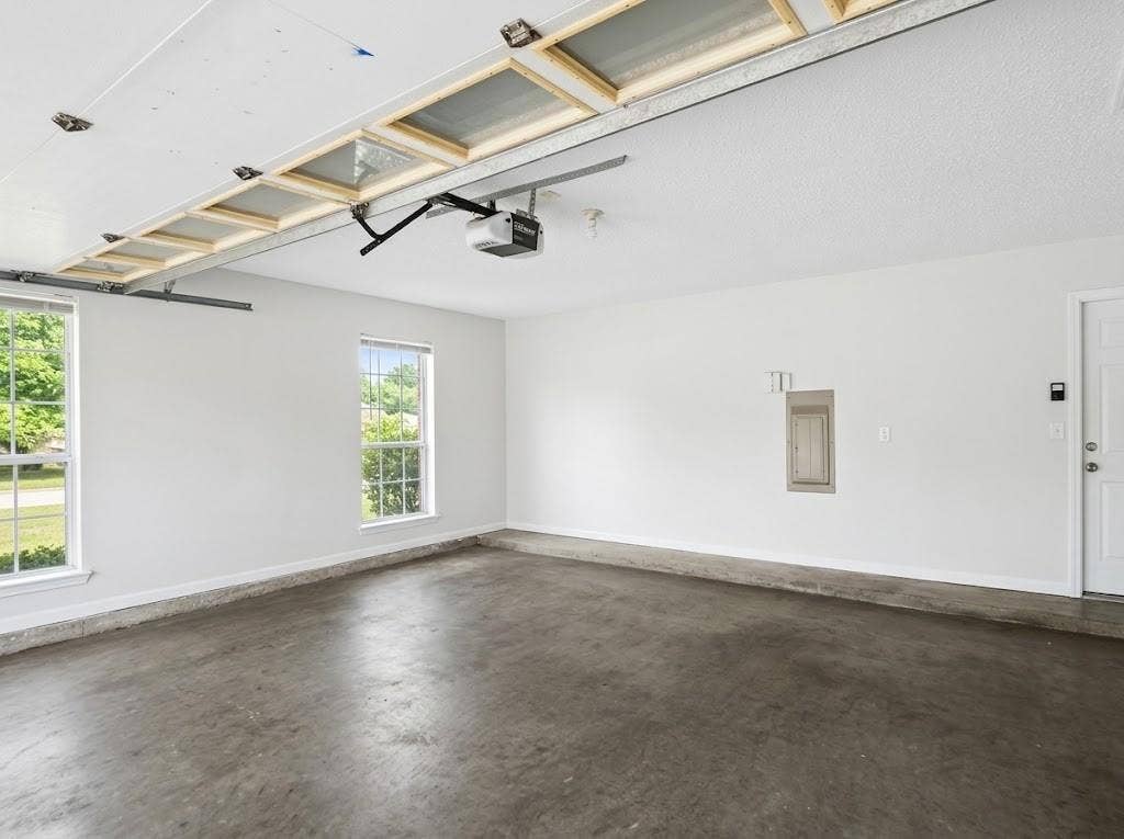 2609 Townshed Drive, Garland, TX 75044 Attached garage with concrete flooring, two windows, and overhead garage door mechanism