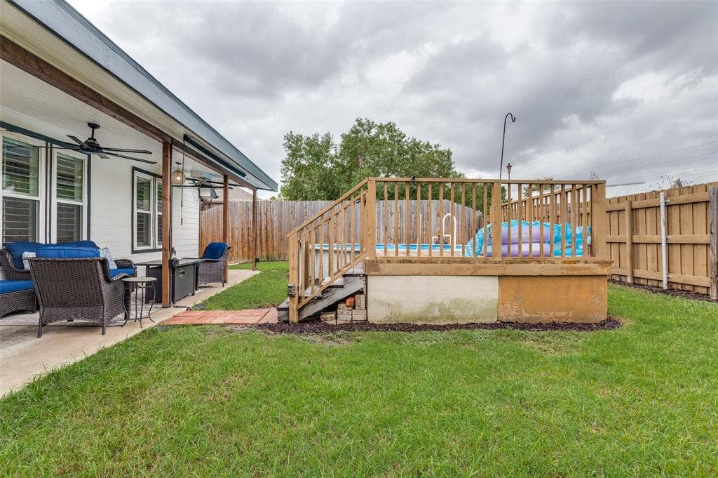Outdoor living area with a covered patio, ceiling fans, and a raised wooden deck with an above-ground pool