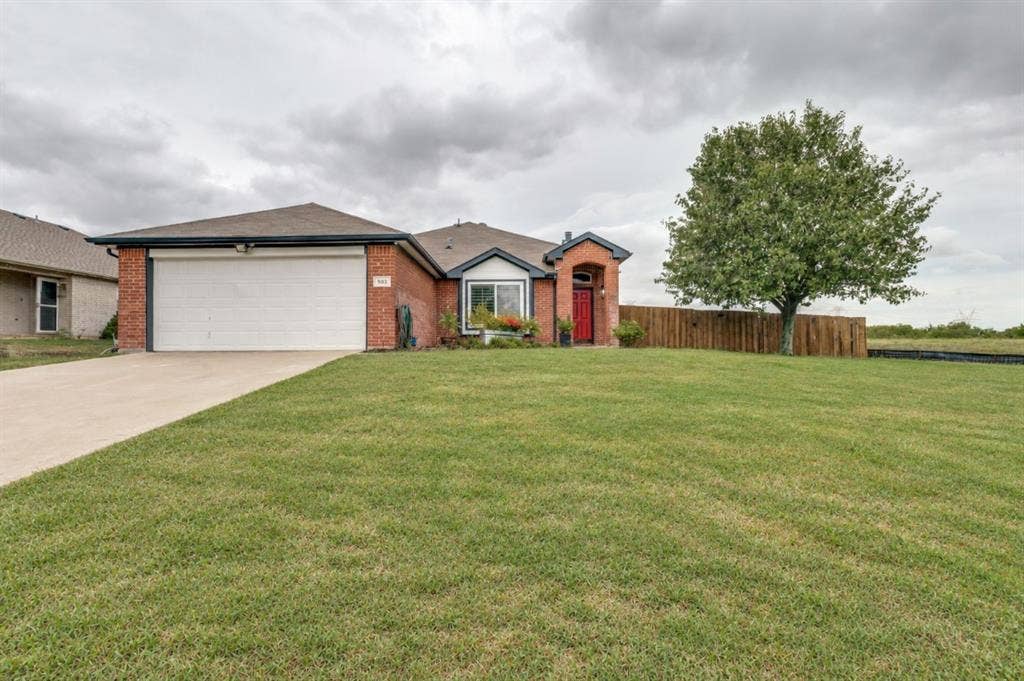 Traditional brick exterior with an attached garage, concrete driveway, and a mature tree